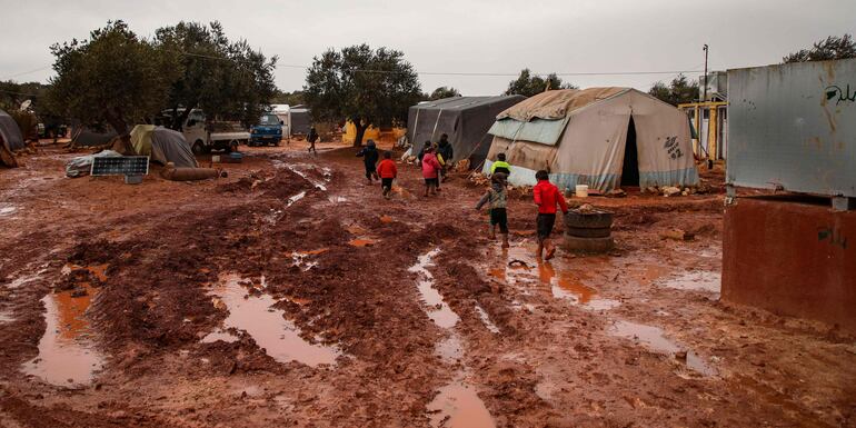 Niños caminan en el barro en un campamento de refugiados cerca de la aldea de Killi, en el norte de la provincia siria de Idlib.