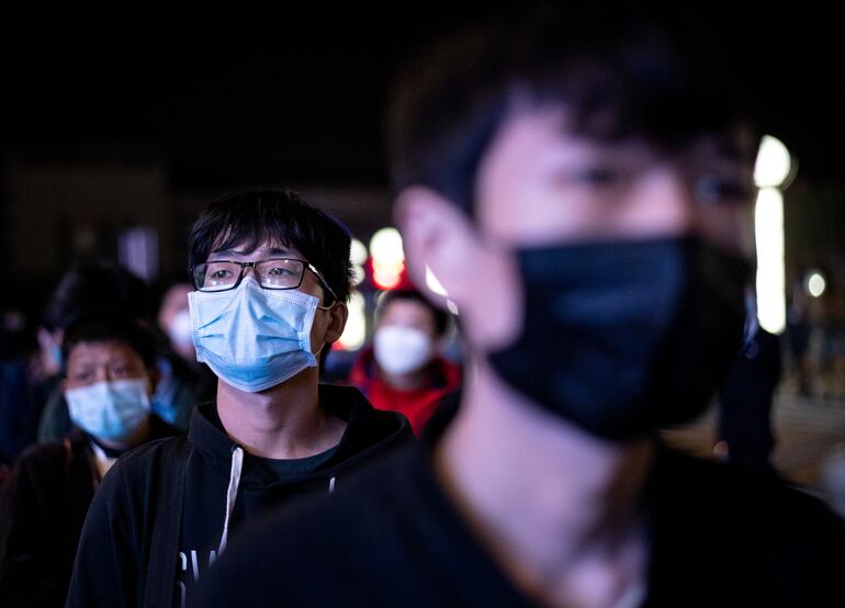 Pasajeros con mascarillas hacen fila en una estación de trenes en Wuhan, China.