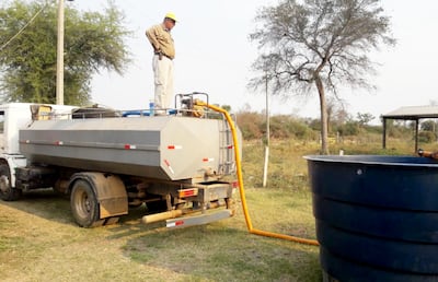 Personal de la empresa contratista encargada de reparar camino de tierra en la zona de Fuerte Olimpo provee de agua a la población. A los incendios se suma la escasez del vital líquido.