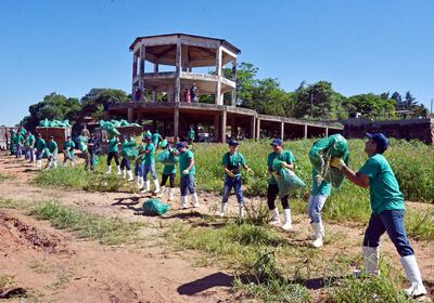 La cadena humana de los colaboradores de Athena Foods para recoger la basura a orillas del río Paraguay. La jornada de limpieza se realizó en la ciudad de San Antonio.