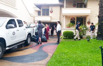 Ramón González Daher se sostiene de una de las dos camionetas de la Fiscalía, mientras se cargaban bolsas grandes y cajas que contenían evidencias que se incautaron de su mansión.