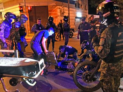 Un paramédico asiste  al policía accidentado ante la   mirada de otros miembros de la misma unidad que llegaron al sitio.