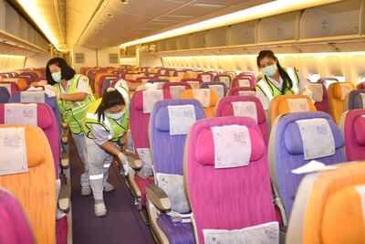 Miembros del staff de Thai Airways desinfectan una aeronave.