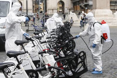 Trabajadores desinfectan bicicletas públicas en Roma. Italia experimentó un repunte en la cifra de fallecidos diarios.