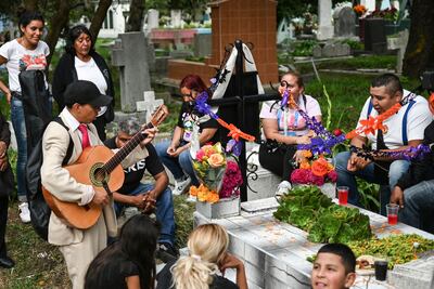 Una familia se reúne en torno a la tumba de un familiar en un cementerio de la ciudad de México.