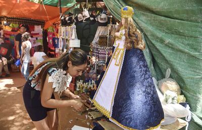 Ramona Belotto  trabaja sin descanso en vestir figuras de la Virgen. Es que es la época de mayor demanda y existen pedidos desde varias ciudades del país, dice en su puesto de Tupãsy Ykua.