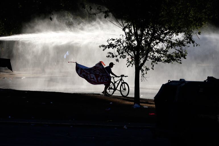Fuerzas Especiales de Carabineros dispersan a un grupo de manifestantes este domingo en la céntrica plaza Italia de Santiago (Chile).