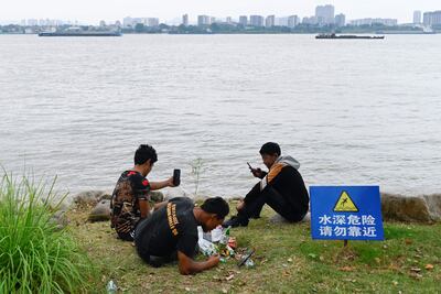 Un grupo de hombres mira sus teléfonos frente al río Yangtze en Nanjing, provincia de Jiangsu, en China.