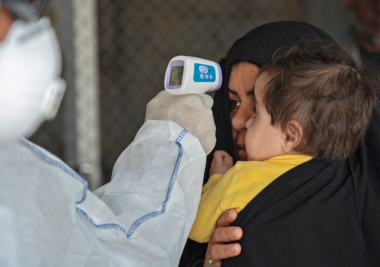 Un médico revisa la temperatura de viajeros en Shalamjah, Irak.
