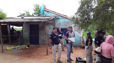 El cuerpo sin vida de Derlis Javier Burgos Fariña yace cubierto con una sábana y bajo custodia policial frente a la vivienda donde trató de refugiarse, después de ser baleado en la espalda.