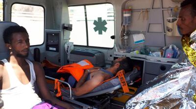 Dos de los migrantes que se arrojaron al mar desde el barco en un intento de llegar a la costa son atendidos en una ambulancia.