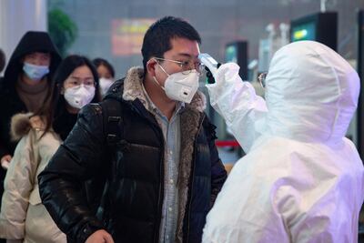 Un médico revisa la temperatura de un hombre en la estación de trenes del sur de Nanking, China.