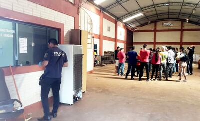 Un oficial de Policía recoge algunas evidencias del lugar del hecho. En tanto que los trabajadores comentan lo ocurrido.