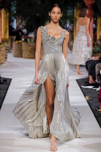 Vestido joya plisado en plata iridiscente, con apliques de flores brillantes y abertura frontal. (Foto Showme That, EFE).