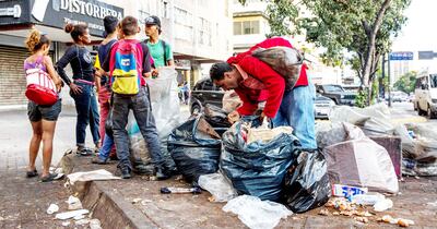 Personas buscando comida entre bolsas de basura en Venezuela, uno de los países más empobrecidos de la región.
