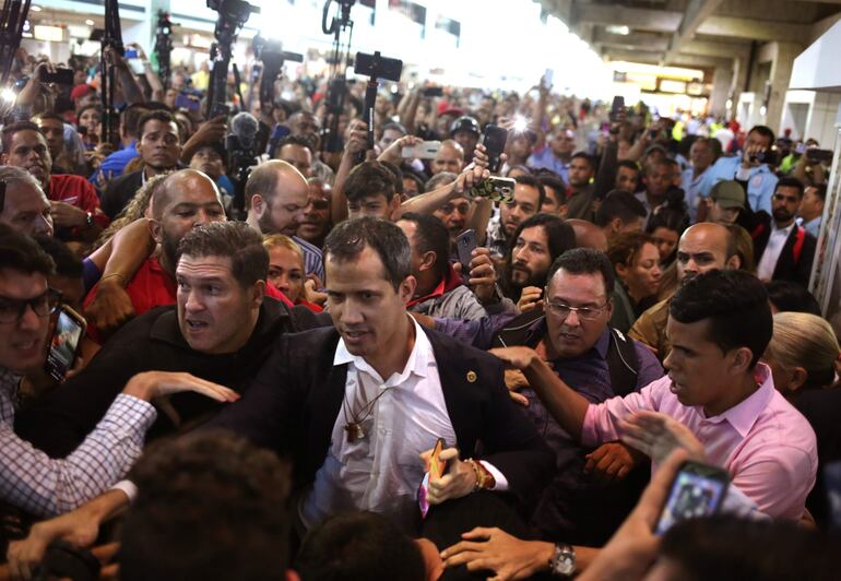 TOPSHOT - Venezuelan opposition leader and self-proclaimed acting president Juan Guaido (C) arrives at Simon Bolivar International Airport in Maiquetia, Vargas state, Venezuela on February 11, 2020. - Guaido returned to Venezuela after a 23-day international tour to revitalize pressure on President Nicolas Maduro, his press team announced. (Photo by Cristian Hernandez / AFP)