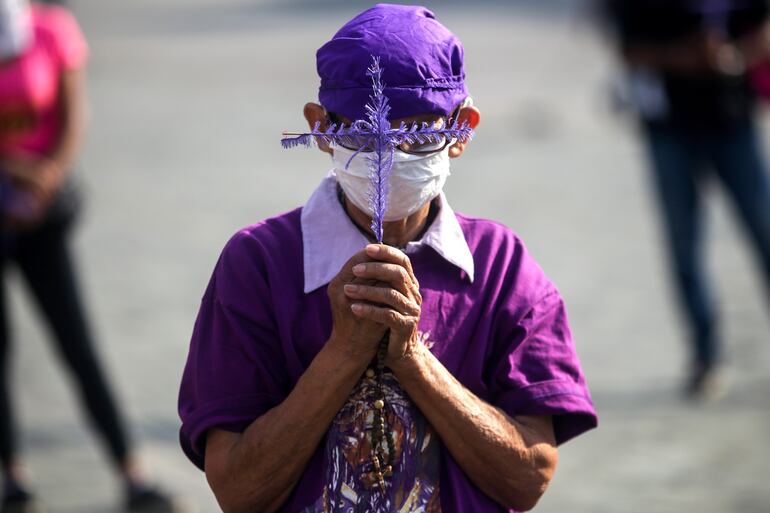 Un hombre con mascarilla reza durante una procesión religiosa en Caracas, Venezuela.