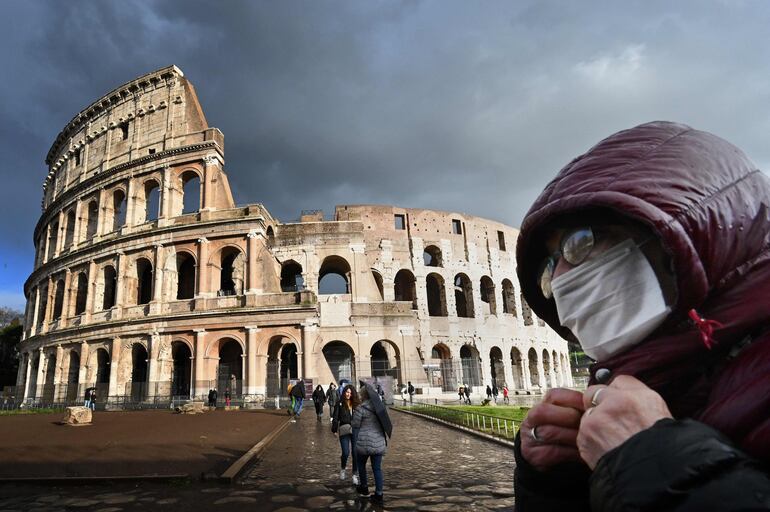 Un hombre con una máscara camina cerca del Coliseo romano.