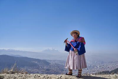Teodora Magueno, escaladora y guía de montaña, posa con la cima del Illimani y la ciudad de La Paz de fondo.