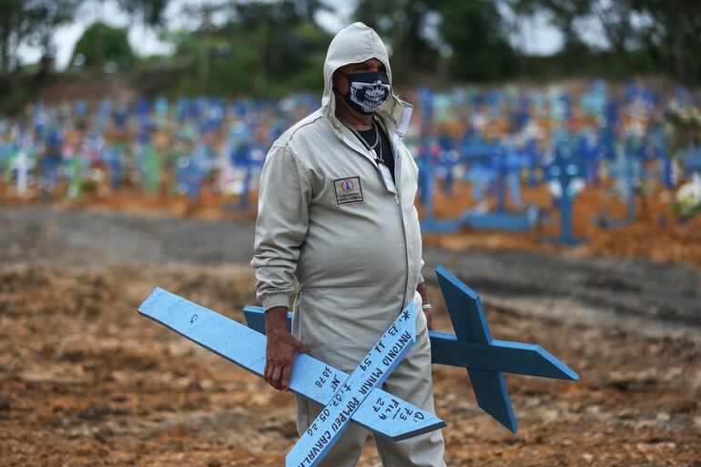Un trabajador del cementerio Nossa Senhora de Manaus, Brasiil, lleva cruces para colocar en tumbas.