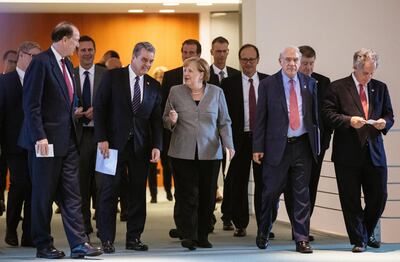 La canciller alemana, Ángela Merkel (c) conversa con el presidente del Banco Mundial David Malpass (con papel en la man) junto a otros miembros de la Organización Mundial del Comercio.