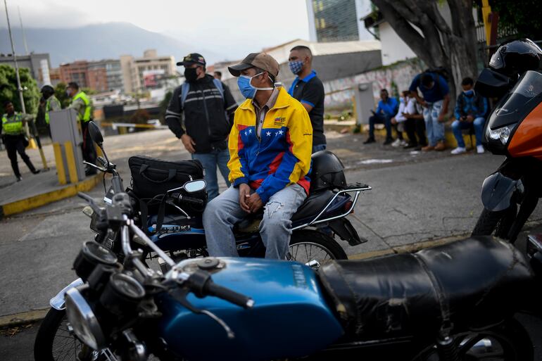 Un motociclista espera en fila para cargar combustible en una estación de servicios en Caracas.