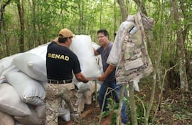 el-fiscal-carlos-alcaraz-y-un-agente-especial-de-la-senad-levantan-algunas-de-las-bolsas-cargadas-con-marihuana-picada-que-fueron-halladas-en-kamba-re-230811000000-1565336.jpg