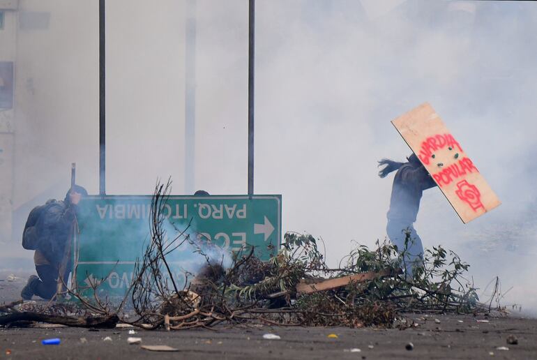 Manifestantes se cubren durante un enfrentamiento con la policía en Quito.