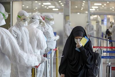 Personal médico entrega folletos informativos sobre el coronavirus a pasajeros que arribaron desde Irán, en el Aeropuerto Internacional Najaf de Bagdad, Irak.