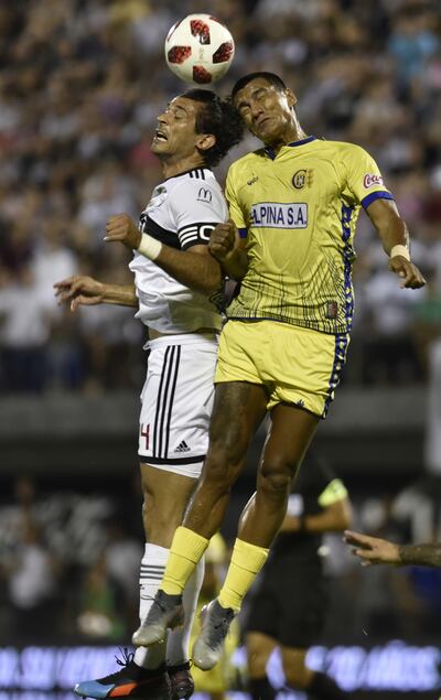 Roque Santa Cruz, el jugador distinto del fútbol paraguayo, por su formación europea y su físico privilegiado, salta con el defensor de Capiatá, Jorge Paredes. El siempre fiable, Roque, anotó el gol de la victoria.