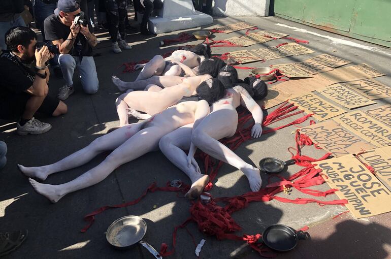 Manifestantes desnudos con los cuerpos pintados de blanco portan este lunes carteles con los nombres de los 20 fallecidos en las protestas de Chile, este lunes frente a una comisaría de Carabineros, en Santiago (Chile).