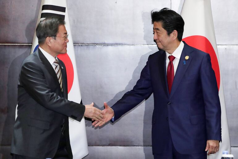 El presidente surcoreano Moon Jae-in (i) y el primer ministro japonés Shinzo Abe se saludan durante la cumbre en Chengdu.