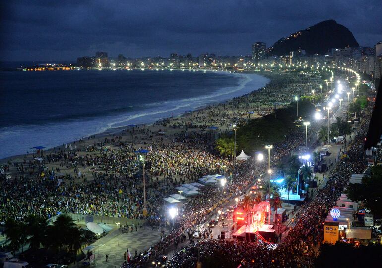 Faithfuls crowd Copacabana beach as Pope Francis arrives on the popemobile (C, bottom) to participate in a re-enactment of the 14 Stations of the Cross -- scenes of Jesus carrying the cross to his crucifixion -- in Rio de Janeiro, on July 26, 2013. Pope Francis, who is in Rio for the weeklong gathering of young Catholics World Youth Day, took his high-octane mission to "shake up" Catholic faith back to the streets of Brazil Friday, greeting throngs of pilgrims, meeting convicts and hearing youngsters confess their sins.  AFP PHOTO / VANDERLEI ALMEIDA
