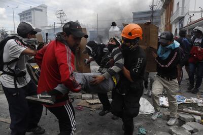 Manifestantes ayudan a un hombre afectado durante las confrontaciones con la policía cuando se cumplen 10 días de protestas contra el Gobierno este sábado, en Quito (Ecuador).