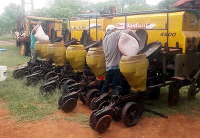 Dos productores cargan las tolvas de las sembradoras que están listas para hacer su trabajo.