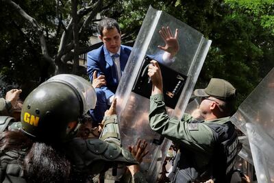 El líder opositor venezolano Juan Guaidó trepa una reja en un intento por ingresar a la sede de la Asamblea Nacional, custodiada por la policía para impedir su ingreso y el de diputados opositores este domingo, en Caracas (Venezuela).