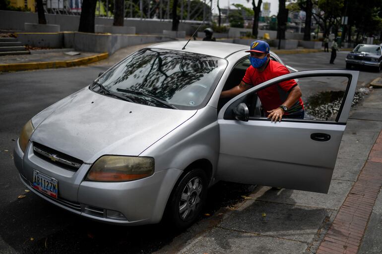 Un automovilista empuja su vehículo mientras espera en fila para cargar combustible en Caracas.