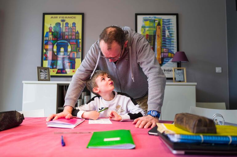 Un padre acompaña a su hijo en las tareas escolares, durante su confinamiento contra el coronavirus. 