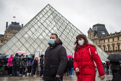 Dos turistas usan máscaras tapabocas mientras pasean cerca de la pirámide del Museo del Louvre, en París, Francia.