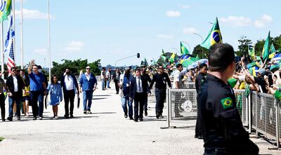El presidente de Brasil, Jair Bolsonaro (izq.) levanta la mano para saludar a sus simpatizantes agolpados ayer en Brasilia.