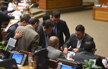 El presidente de la Cámara de Diputados, el cartista Pedro Alliana, conversa con varios de sus colegas, entre los que aparecen Basilio Núñez y Hugo Ramírez. El voto colorado será clave el martes.