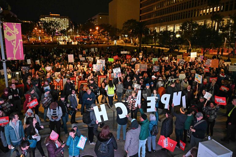 Protesters hold signs calling for the impeachment of US President Donald Trump outside the Los Angeles City Hall building, in Los Angeles, California on December 17, 2019. (Photo by Robyn Beck / AFP)