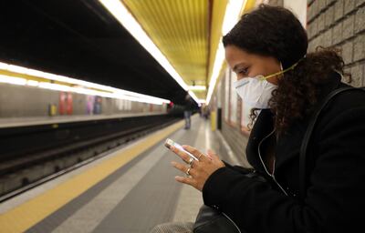 Una mujer con tapabocas espera un tren en una estación del metro en Milán, Italia.