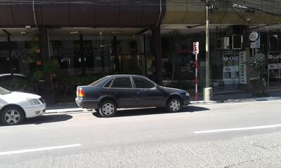 Vehículos estacionados frente a un cartel que prohíbe dicho acto.