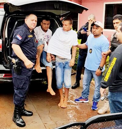 El comisario paraguayo Alexander Méndez (izq.) entrega a los dos brasileños detenidos a agentes de la Policía Civil del país vecino, que los buscaban por un terrible asesinato cometido el fin de semana en Caarapó.