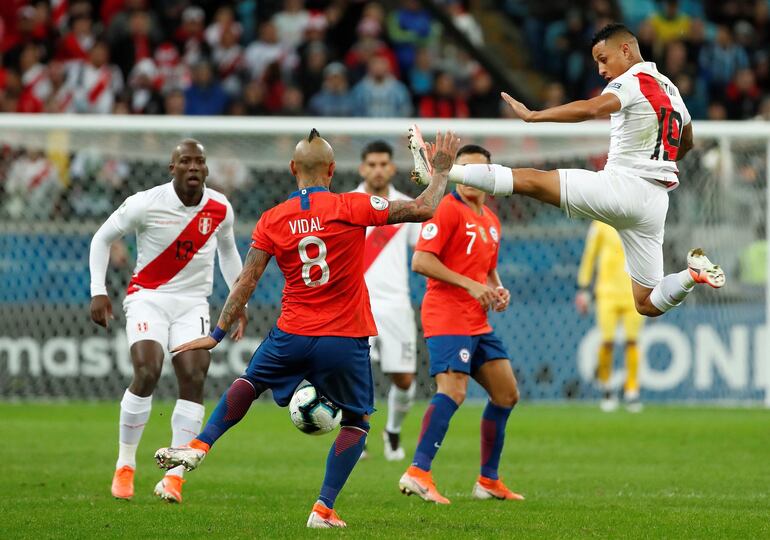 Salto de ballet del peruano Yoshimar Yotún en procura de interceptar un remate del chileno Arturo Vidal, durante el partido que Perú derrotó anoche a Chile para avanzar a la final de la Copa América. Los incas definirán el título el domingo ante Brasil.