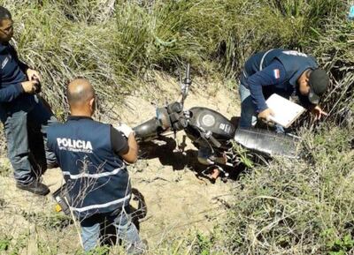 Efectivos policiales verifican la motocicleta Kenton negra que fue abandonada por los sicarios tras matar a Luis Quiñónez Pavón.