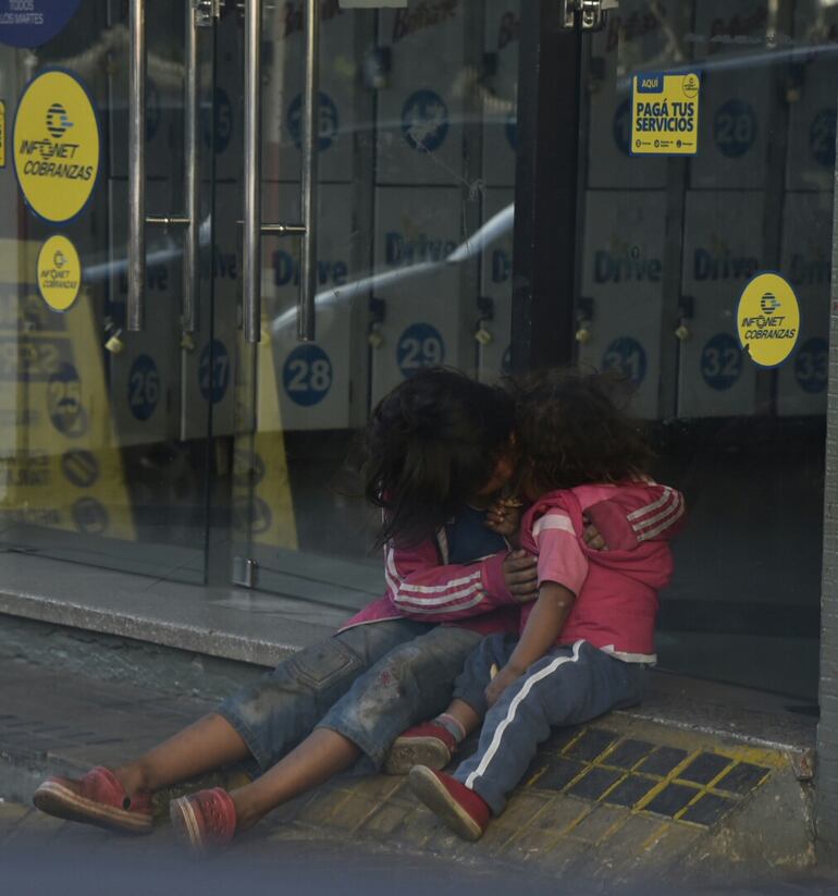 Una niña indígena abraza a su hermanita, que viste apenas una remera de mangas cortas, para protegerla del frío. Fue esta mañana, en el microcentro, cuando el termómetro marcaba apenas 7°C.