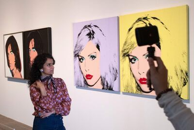 Una asistente de la Tate Gallery posa frente a los cuadros "Debbie Harry", pintados por Andy Warhol en 1980.