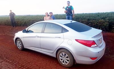 Agentes policiales custodian el automóvil Hyundai, que fue abandonado en medio de un sojal.